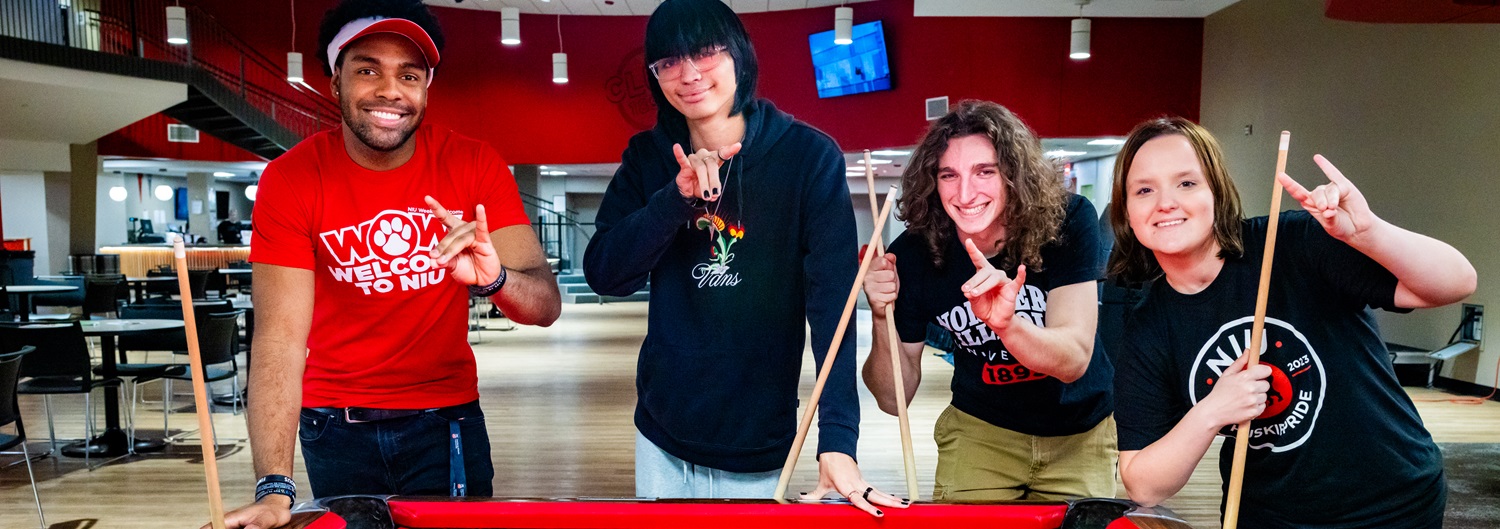 Smiling students play billiards in the Huskie Den
